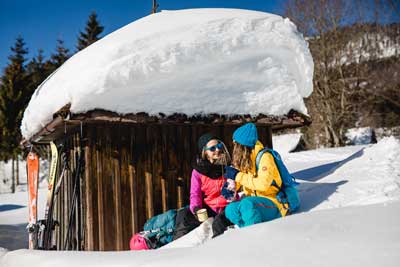 Zwei Damen machen eine kleine Pause nach einer Winterwanderung im Naturpark